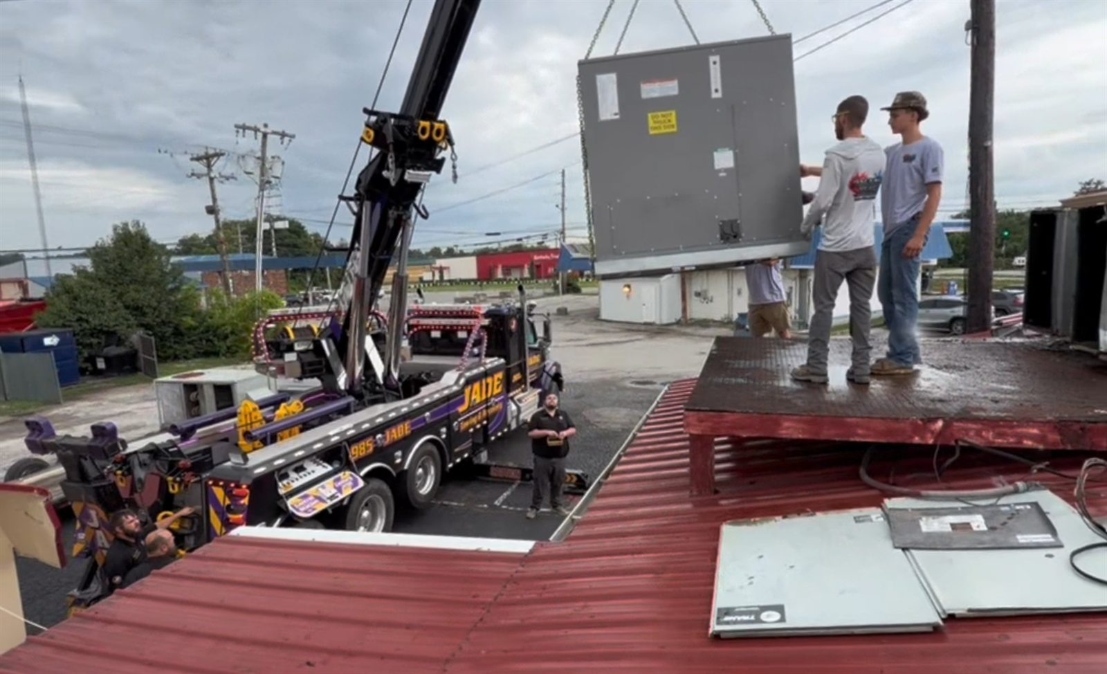 Commercial rooftop HVAC unit being lifted into place by a crane