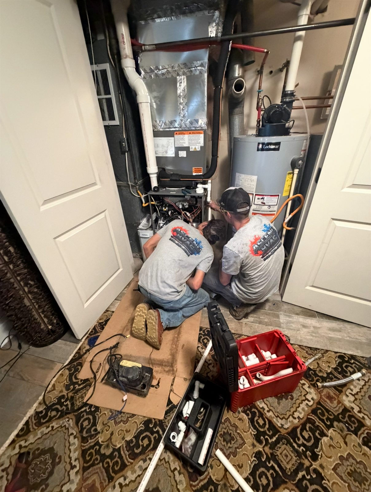 Two Ascend HVAC technicians servicing an indoor heating and cooling system